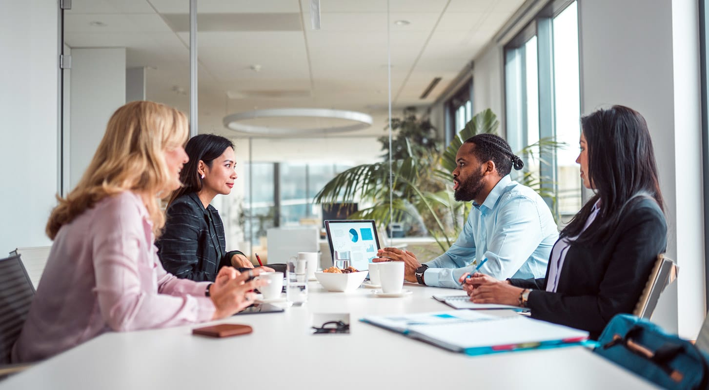 A group of business professionals seated at a conference table, collaborating and sharing ideas during a meeting.